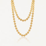 Collier long en acier inoxydable doré, composé de disques ronds martelés, élégamment drapé en deux rangs.