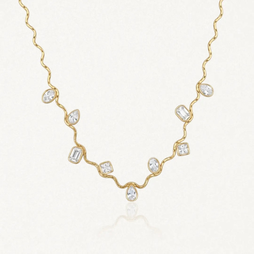 Collier en acier inoxydable dore, chaîne vague avec 9 zircons multiformes (ovales, poire, rectangulaires, carrés) sertis