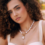 Collier en acier inoxydable doré avec perles baroques blanches, fermoir toggle et perle goutte pendante.