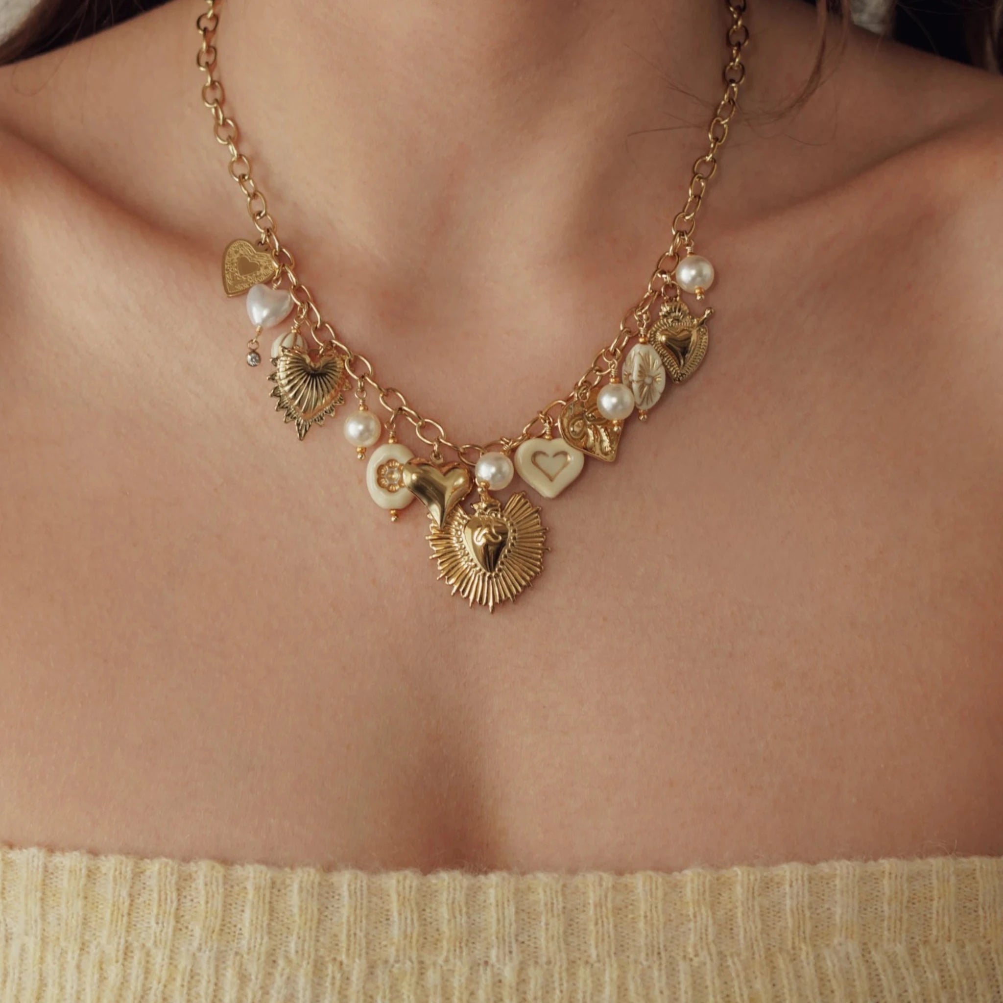 Femme portant le collier à breloques cœurs et perles, mise en avant du style bohème chic et des détails dorés.