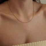 Collier chaîne fine dorée porté seul sur la peau pour un look minimaliste chic ou en base de superposition.