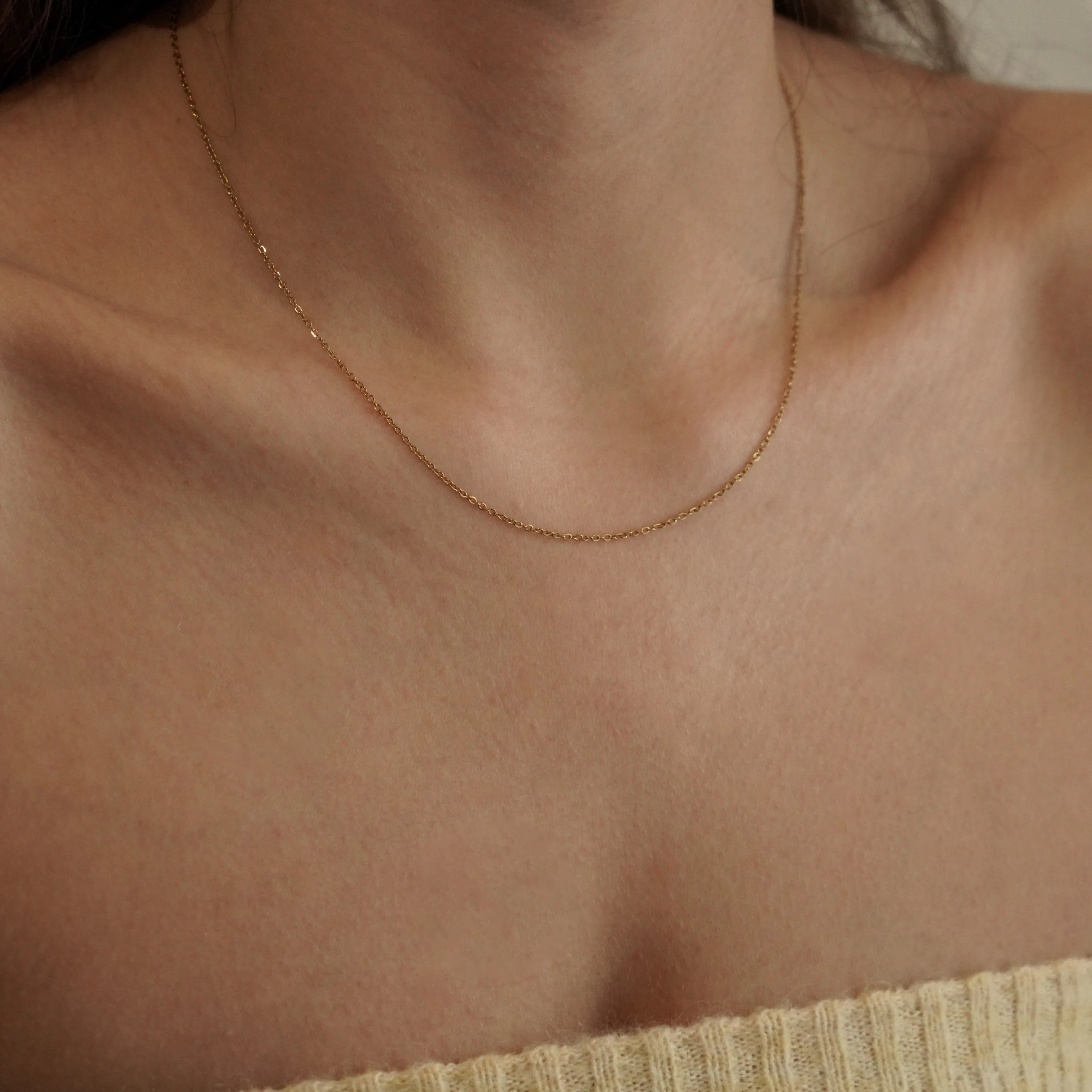 Collier chaîne fine dorée porté seul sur la peau pour un look minimaliste chic ou en base de superposition.