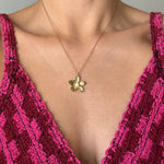 Collier acier inoxydable doré avec pendentif fleur et perle centrale sur le décolleté d'une femme.