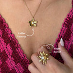 Collier en acier inoxydable doré avec pendentif fleur et perle centrale, porté sur une tenue rose.