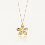 Collier en acier inoxydable doré avec pendentif fleur texturé et une perle au centre.