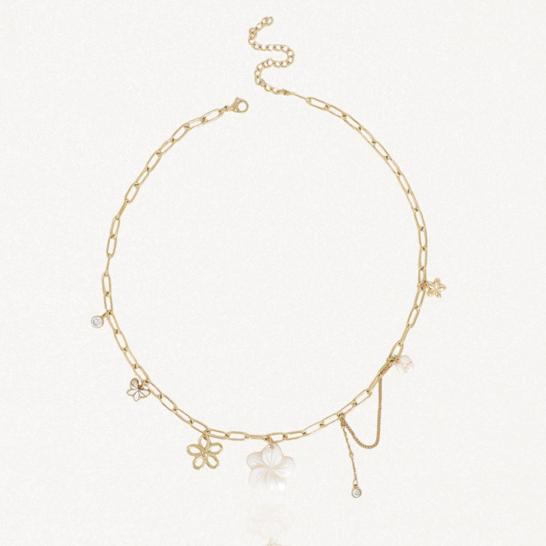 Collier en acier inoxydable doré à maillons allongés, agrémenté de pendentifs fleur de nacre, papillon, perle et cristaux.