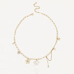 Collier en acier inoxydable doré à maillons allongés, agrémenté de pendentifs fleur de nacre, papillon, perle et cristaux.