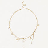 Collier en acier inoxydable doré à maillons allongés, agrémenté de pendentifs fleur de nacre, papillon, perle et cristaux.