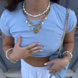 Collier double rang en acier inoxydable dore. Rang de perles, et rang avec charms soleil, piece, coeurs, fleur, et perles.