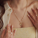 Collier en acier inoxydable doré avec pendentif fleur en 3D et perles fines, porté par une femme.