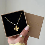 Collier en acier inoxydable doré avec pendentif trèfle et perles, présenté dans une boîte cadeau.