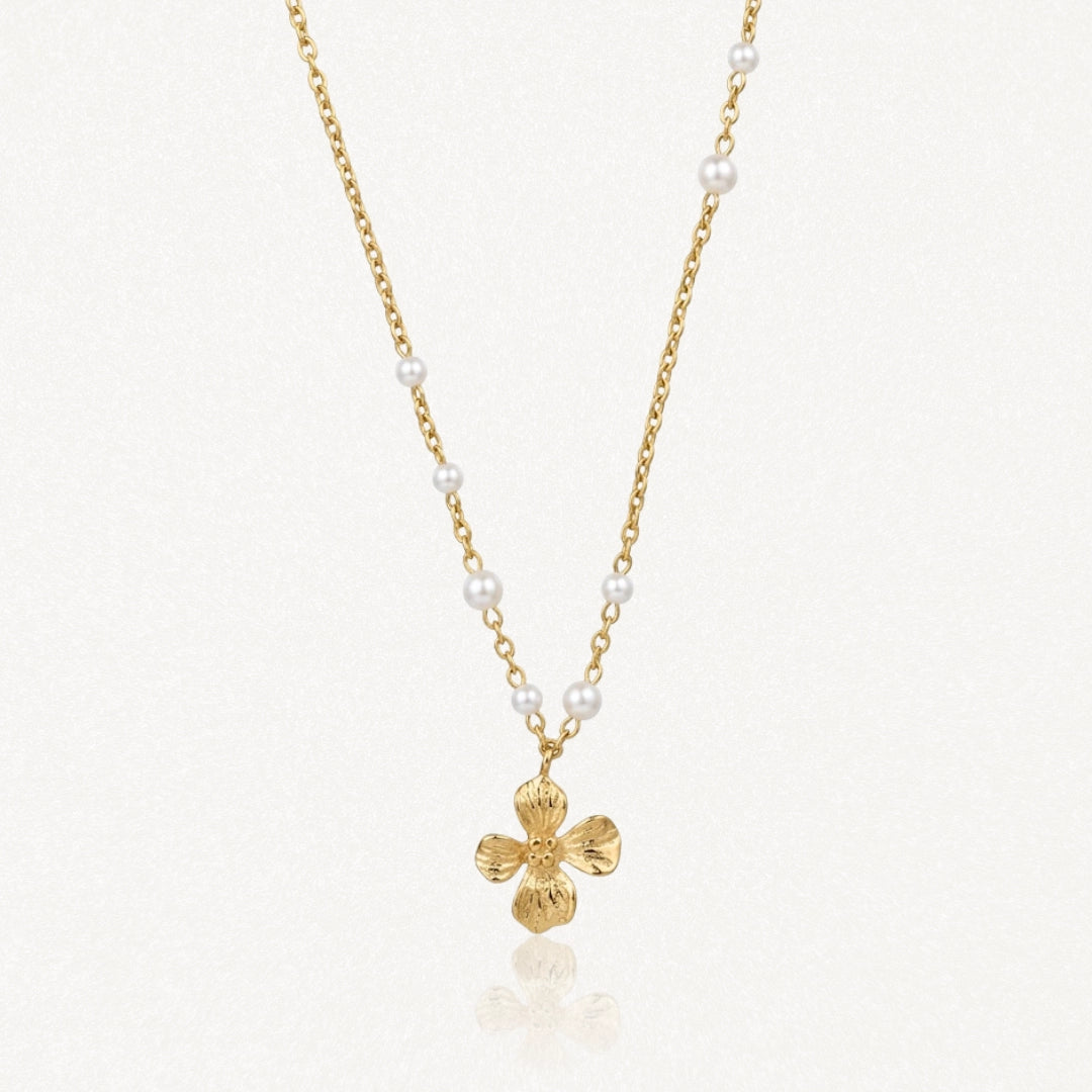 Collier en acier inoxydable doré avec perles blanches et pendentif fleur texturée.