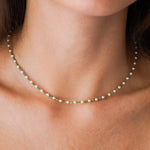 Collier composé de perles blanches, de petites apatites turquoise et de perles rondes en acier inoxydable doré.