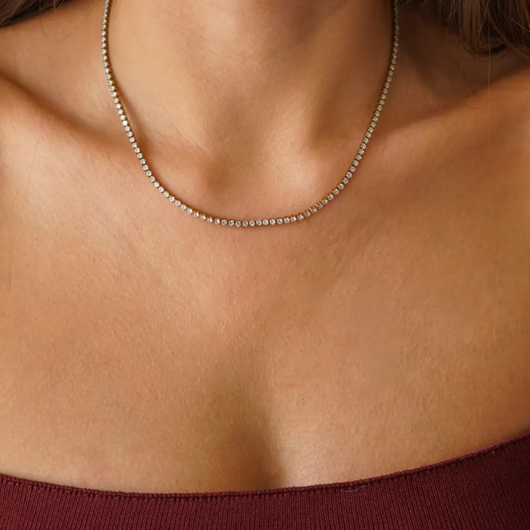 Collier rivière tennis en acier inoxydable doré, serti de petits zircons brillants, porté au cou.