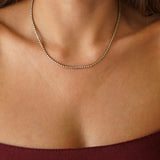 Collier rivière tennis en acier inoxydable doré, serti de petits zircons brillants, porté au cou.
