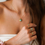 Collier fin avec pendentif soleil en Amazonite et acier inoxydable doré, porté par une femme. Trois bagues en acier