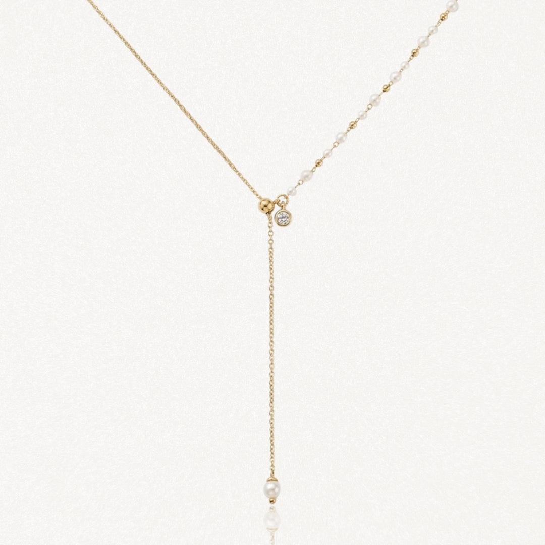 Collier lariat en acier inoxydable doré avec perles, petits détails dorés et zircon. Pendentif chaîne avec perle finale.