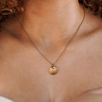 Collier acier inoxydable doré, pendentif coquillage avec 2 perles et un zircon, porté.