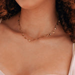 Collier en acier inoxydable doré avec de multiples pendentifs coquillages porté par une femme.