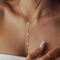 Collier cravate plongeant en acier inoxydable doré orné de petites étoiles du nord scintillantes porté au cou.