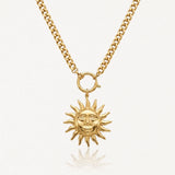Collier acier inoxydable doré, chaîne gourmette et pendentif soleil stylisé avec visage souriant.