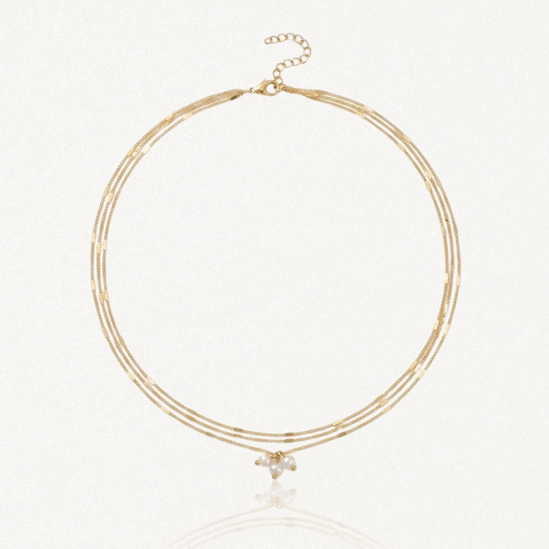 Collier 3 rangs en acier inoxydable doré avec chaînes fines, dont deux à maillons rectangulaires et grappe de perles.