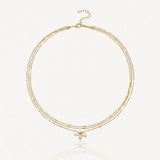 Collier 3 rangs en acier inoxydable doré avec chaînes fines, dont deux à maillons rectangulaires et grappe de perles.