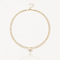 Collier 3 rangs en acier inoxydable doré avec chaînes fines, dont deux à maillons rectangulaires et grappe de perles.
