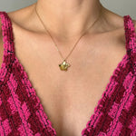 Collier en acier inoxydable doré, pendentif fleur détaillé, porté sur un décolleté.