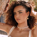 Collier ras-du-cou en acier inoxydable orné de perles blanches irrégulières, porté par une femme.