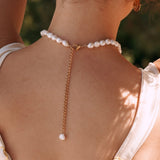 Collier de perles baroques en acier inoxydable doré, porté sur un dos, avec fermoir mousqueton et perle au bout de