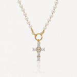 Collier en acier inoxydable doré avec perles blanches, pendentif croix orné de pierres transparentes rectangulaires.