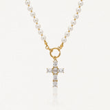 Collier en acier inoxydable doré avec perles blanches, pendentif croix orné de pierres transparentes rectangulaires.