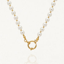 Collier de perles blanches rondes et billes dorées avec fermoir anneau-ressort doré sur fond clair.