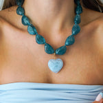 Collier de perles en résine bleu-vert transparentes avec pendentif cœur en résine bleu clair marbré. Acier inoxydable doré.