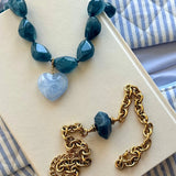 Collier de perles de résine bleu foncé, pendentif cœur en résine bleu clair marbrée, et fermoir en acier inoxydable doré.