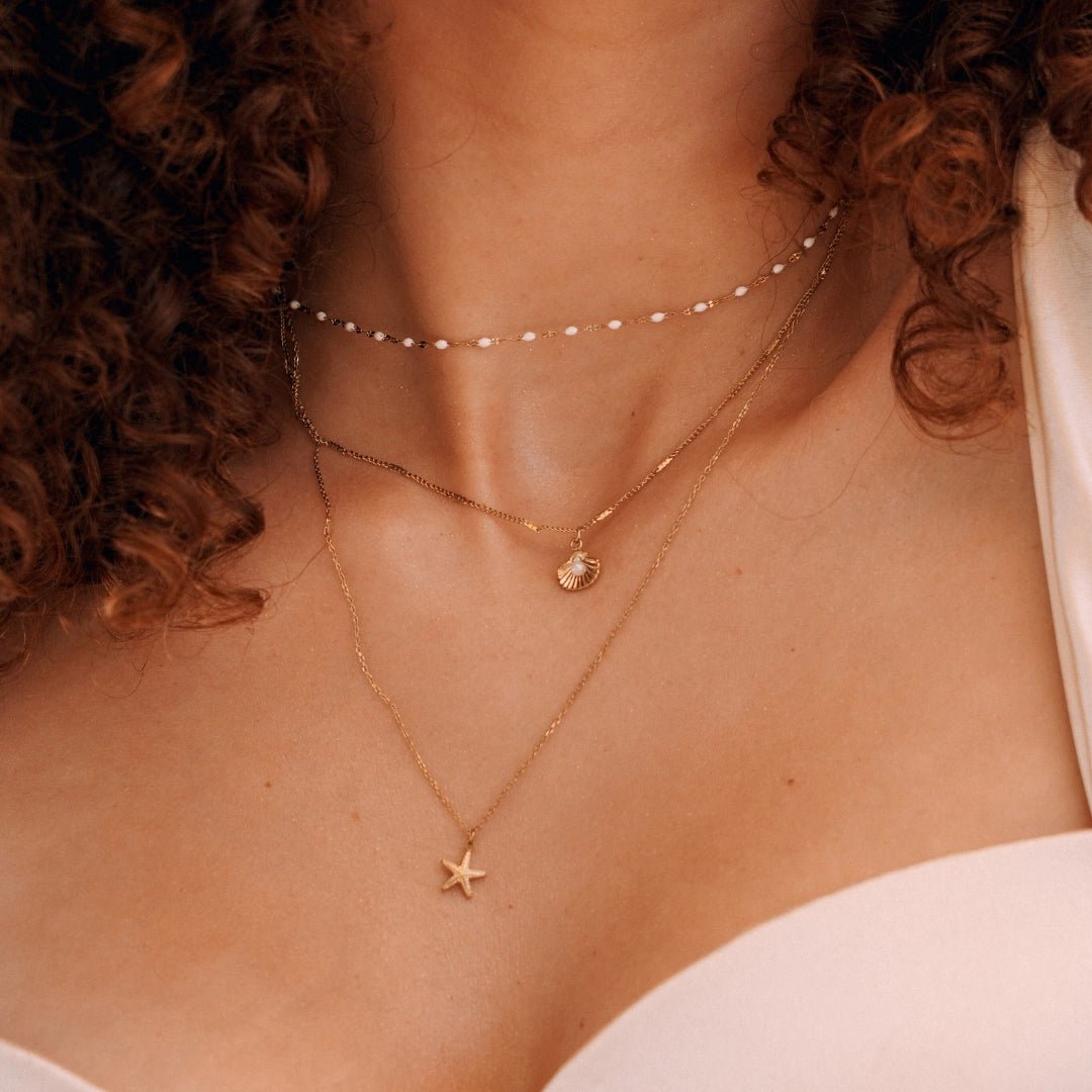 Collier en acier inoxydable doré: 3 chaînes superposées avec perles blanches, pendentifs coquillage perle et étoile de mer.