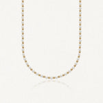 Collier ras-de-cou en perles blanches alternées de billes rondes en acier inoxydable doré.