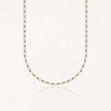 Collier ras-de-cou en perles blanches alternées de billes rondes en acier inoxydable doré.