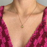 Collier en acier inoxydable doré avec pendentif fleur et son petit détail brillant central, porté au cou.