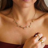 Collier vague en acier inoxydable doré, avec des zircons multiformes sertis clos, porté sur un décolleté féminin.