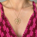 Collier en acier inoxydable doré avec un pendentif fleur ajouré, porté sur un décolleté.