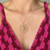 Collier en acier inoxydable doré avec un pendentif fleur ajouré, porté sur un décolleté.