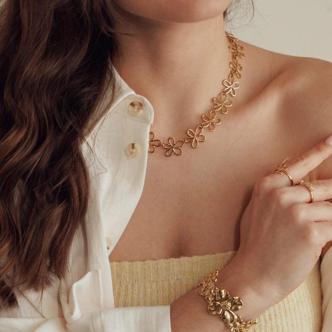 Collier en acier inoxydable doré à motifs de fleurs ajourées porté par une femme.