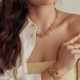 Collier en acier inoxydable doré à motifs de fleurs ajourées porté par une femme.