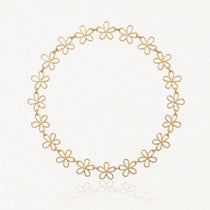 Collier en acier inoxydable doré, composé de maillons ajourés en forme de fleurs, sur fond blanc.