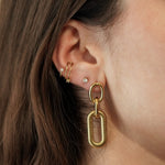 Femme portant les boucles d'oreilles à maillons dorés, accessoire chic et géométrique idéal pour un look moderne.