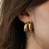 Gros plan sur la boucle d'oreille triple anneaux, bijou hypoallergénique et résistant à l'eau.