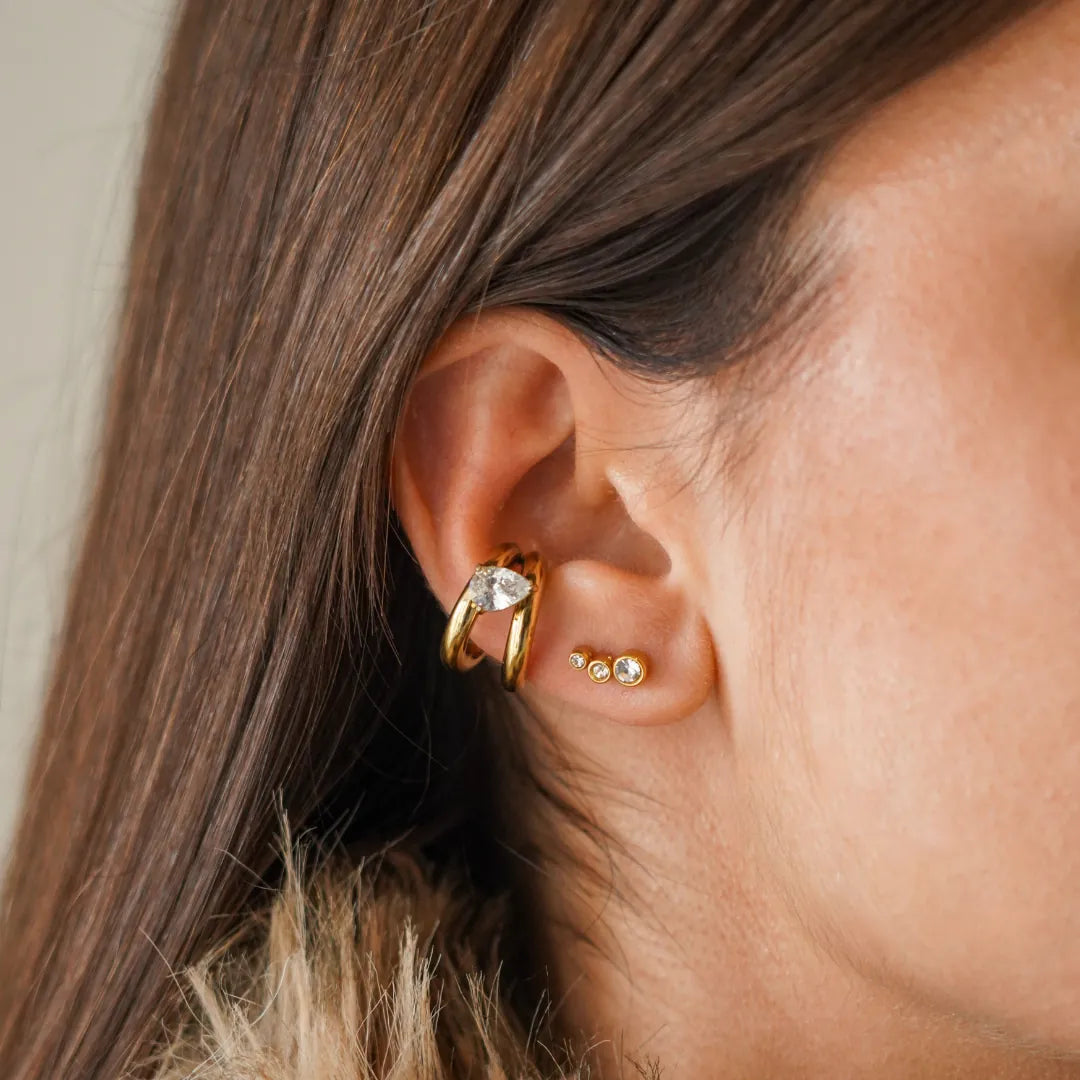 Earcuff mini-créoles doubles en acier inoxydable doré avec zirconium goutte, porté sur une oreille avec 3 mini clous zircon.