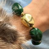 Zoom sur un bracelet porté au poignet, montrant le détail des perles vertes marbrées et de la grosse perle centrale dorée asymétrique.